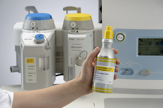A hand holding sevoflurane's aluminium container with machine in the background
